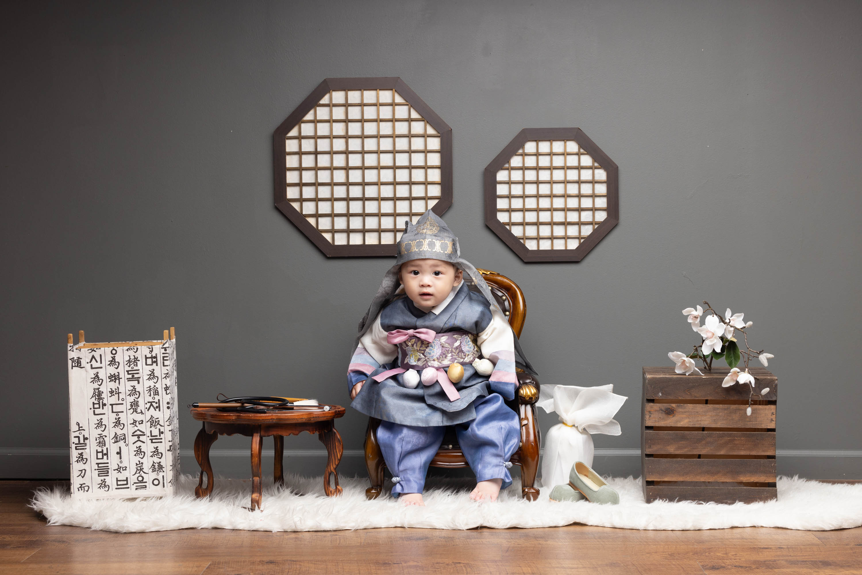 Young child in hanbok seated for a Korean milestone portrait