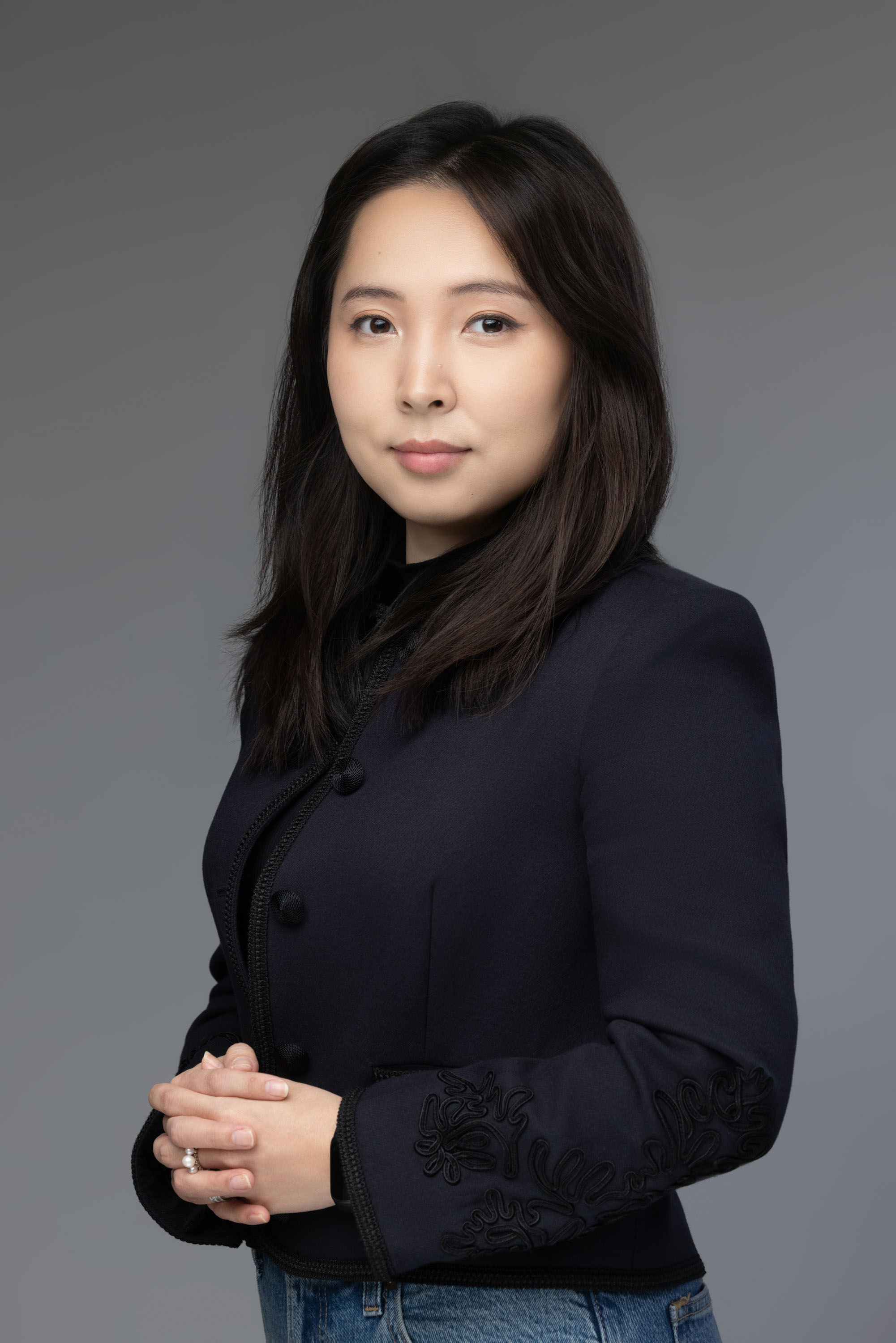 Woman in a dark jacket against a gray background