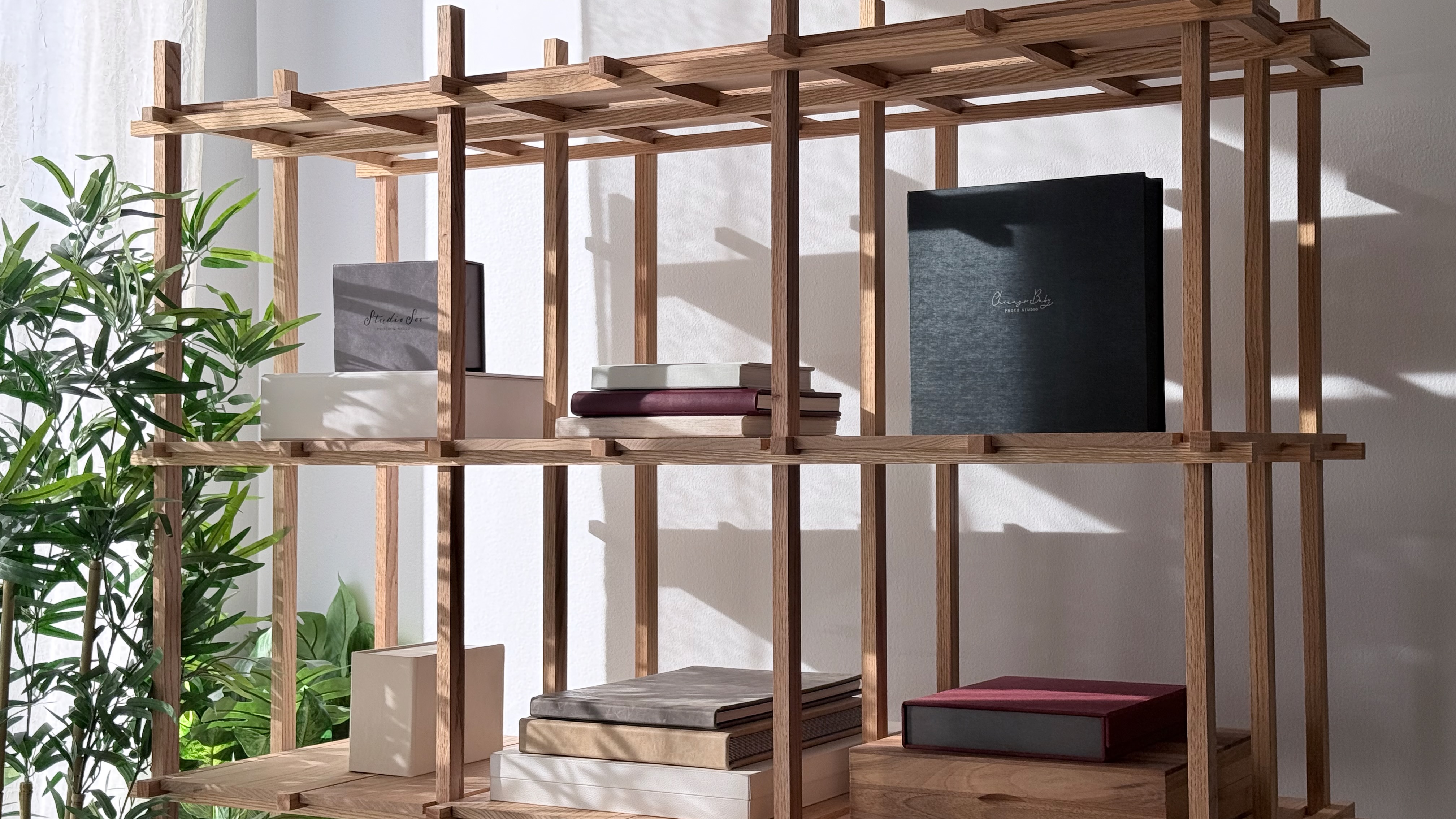 Printed albums and boxes on a sunlit wooden shelf at the studio